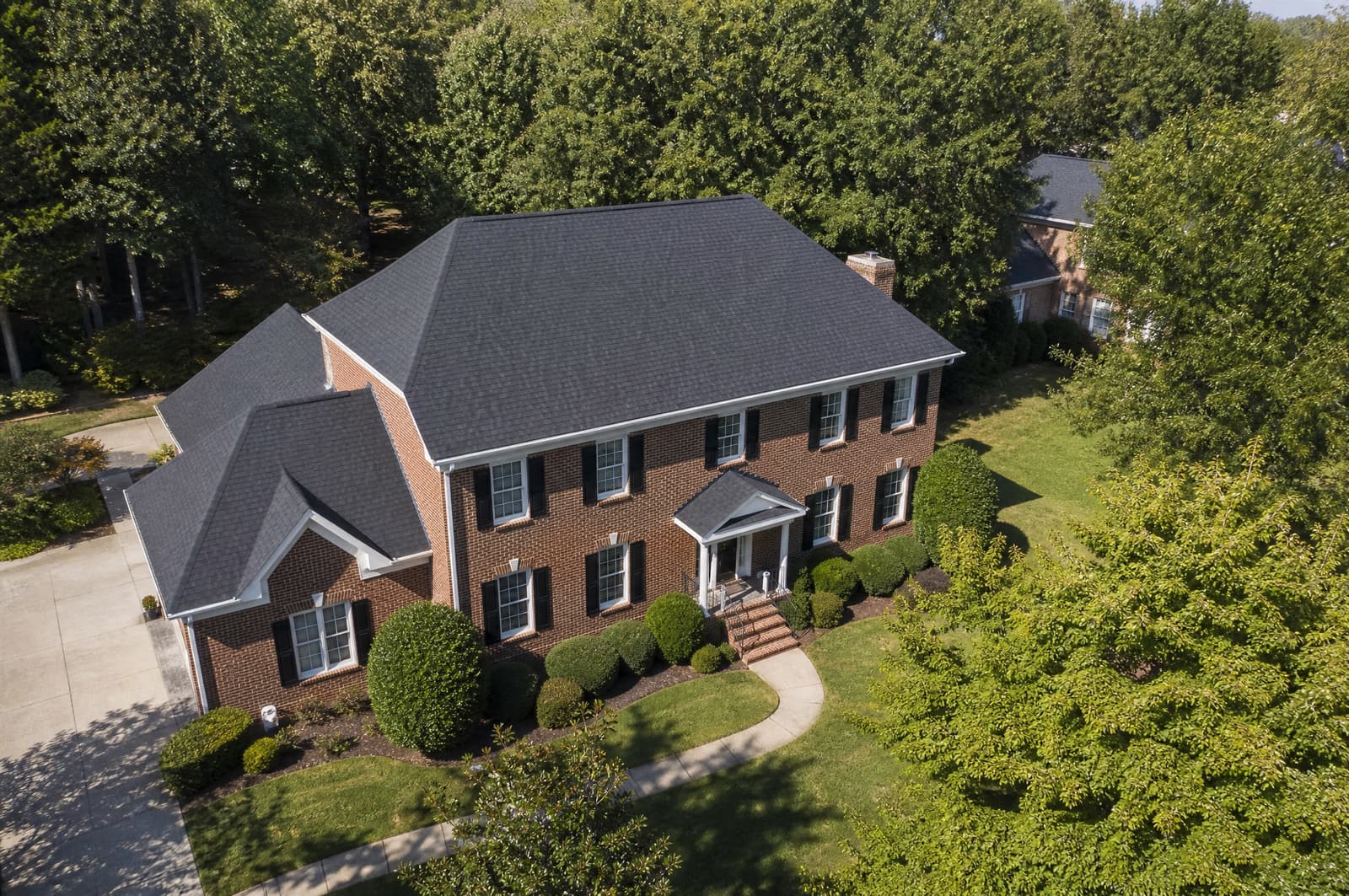 Two-story brick home in Pittsboro, NC with a new charcoal architectural shingle roof, aerial view