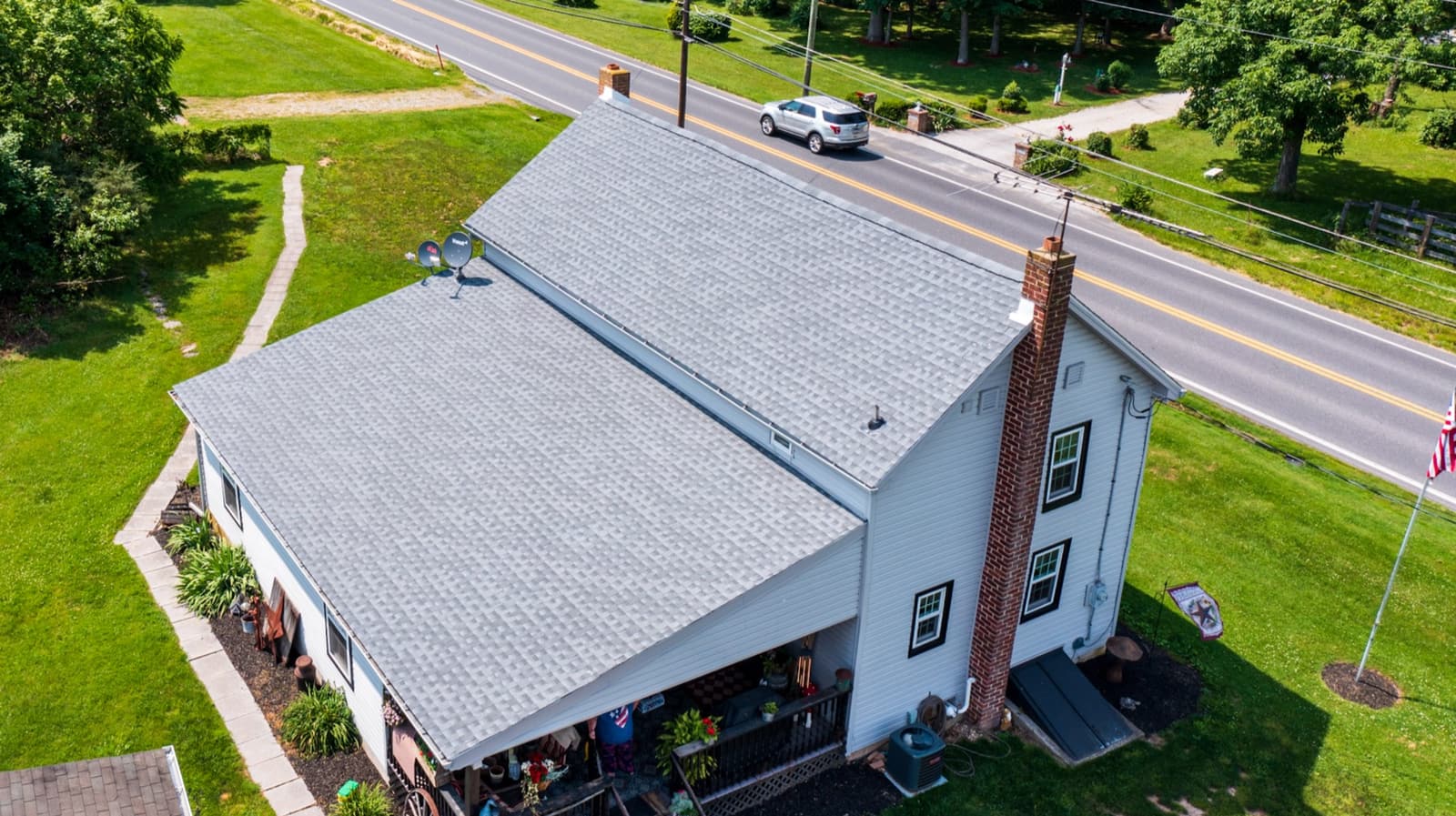 Shingle roof replacement by Skyline on a white farmhouse in Bear Creek, NC, aerial view
