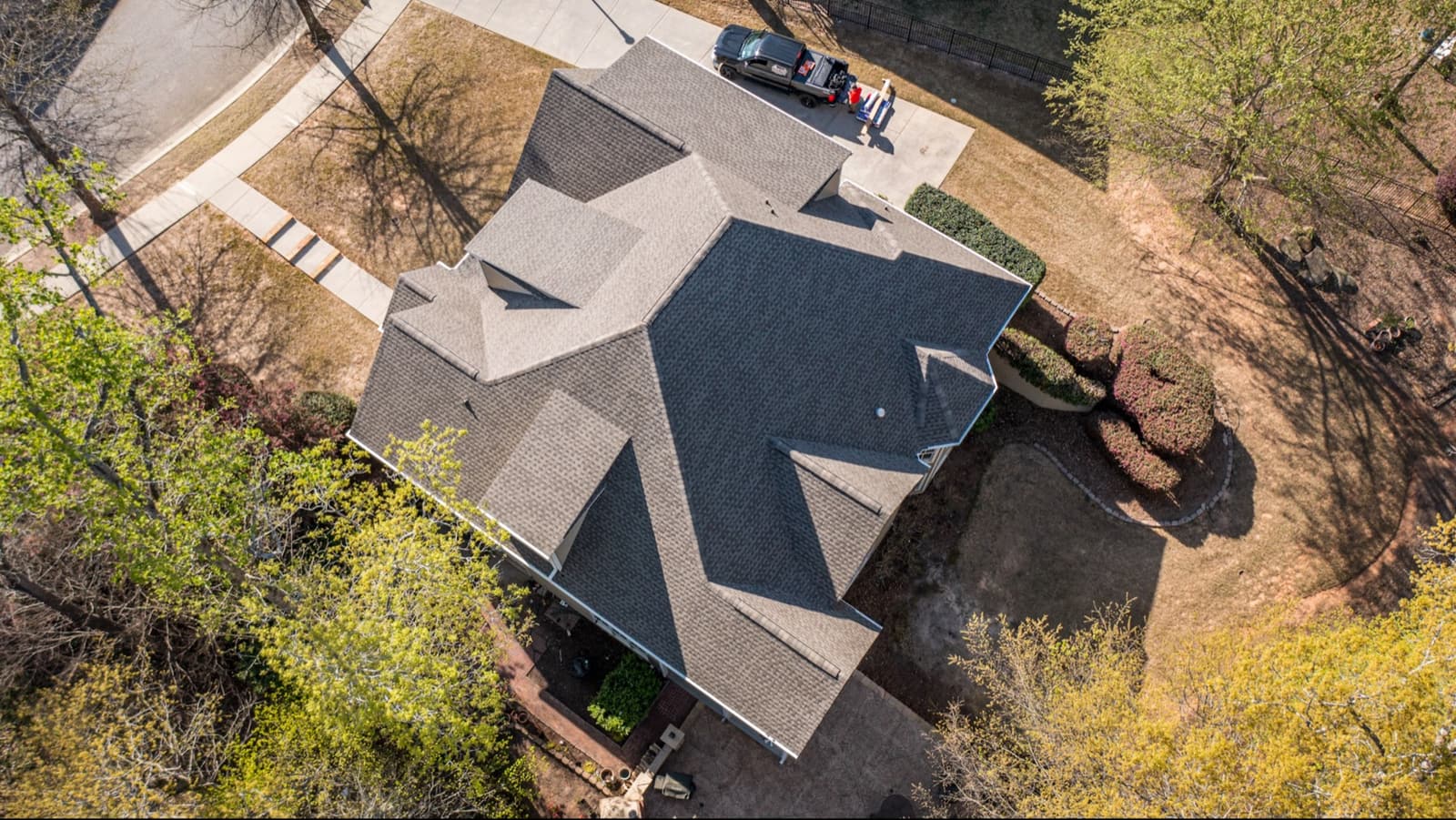 Dark shingle roof replacement by Skyline on a wooded lot in Carrboro, NC, aerial view